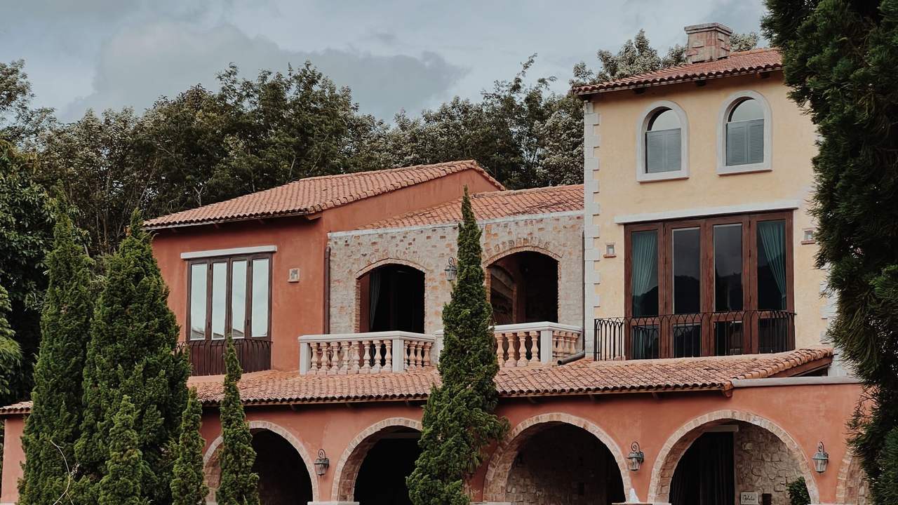 Villa méditerranéenne à arcades et toit de tuiles, entourée de cyprès