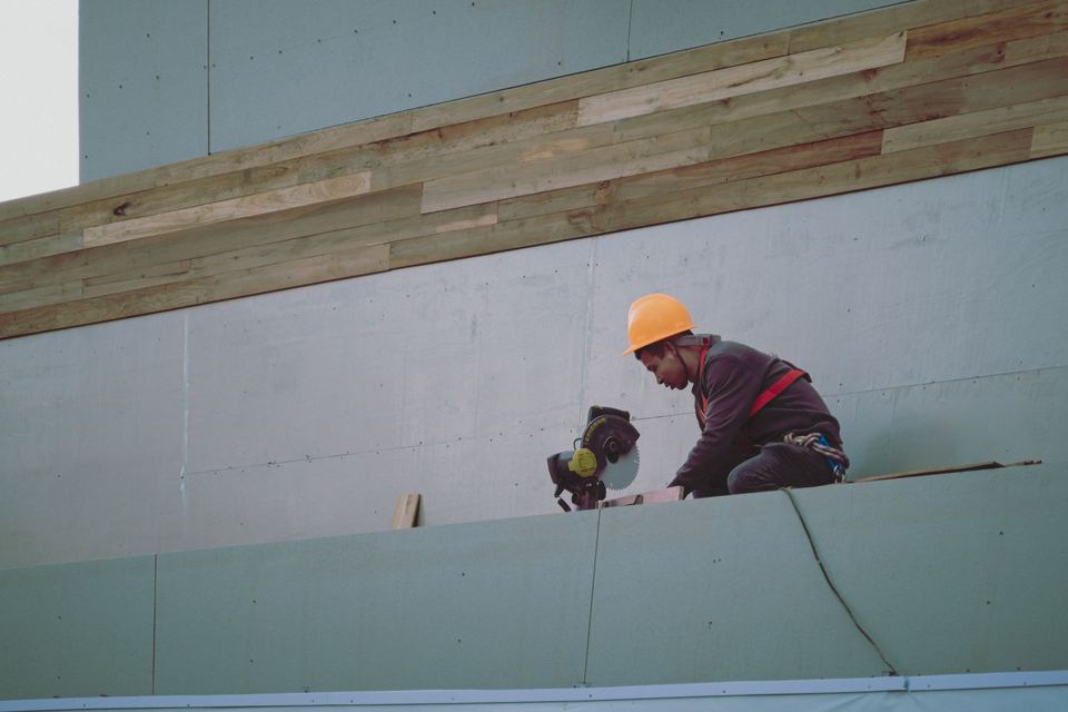 Ouvrier au pied d'un mur de façade en cours d'habillage